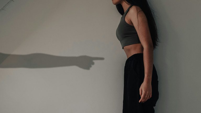 指をさす影に対面する東アジア系女性の横姿